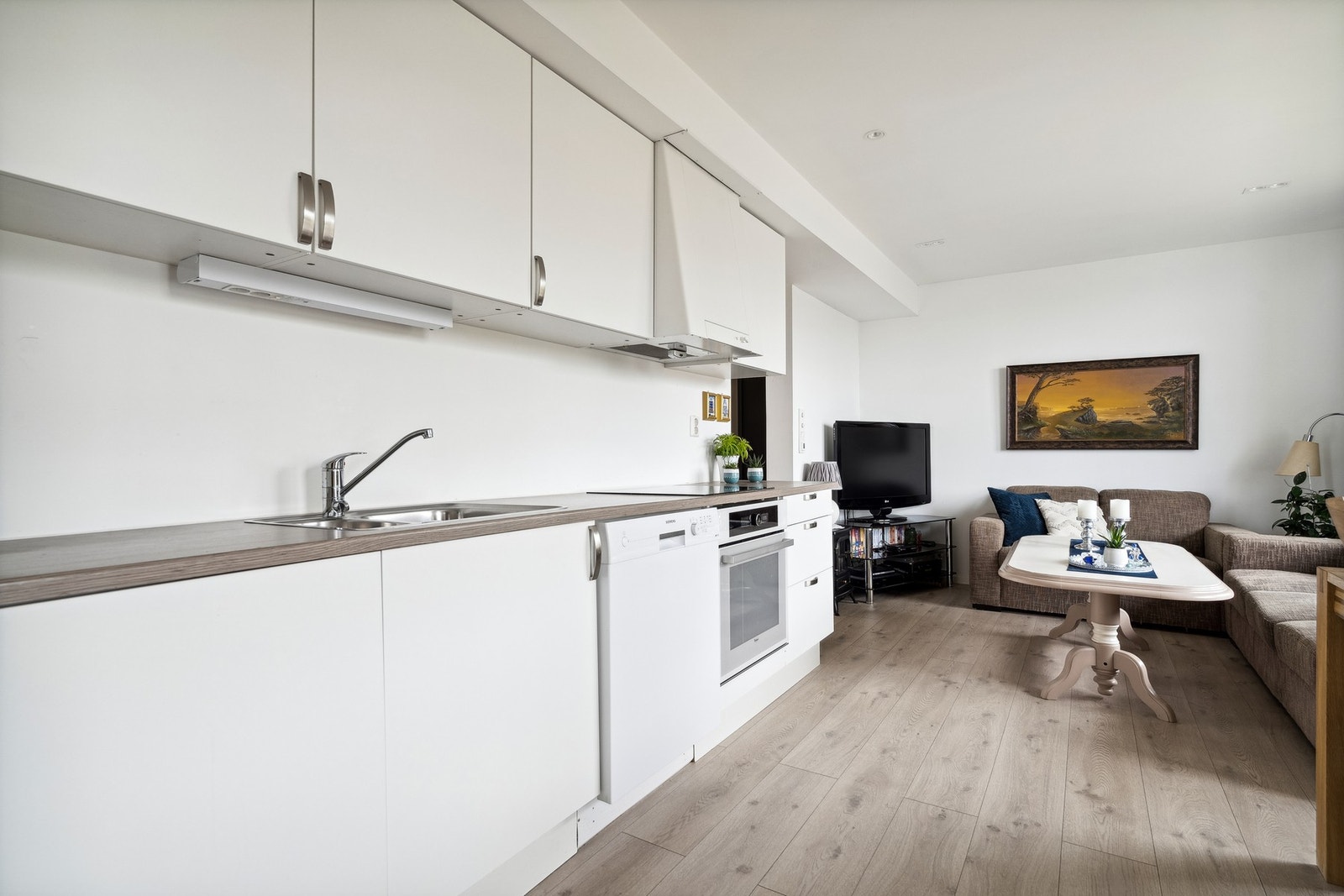 Kjøkkeninnredning med slette fronter og laminert benkeplate - integrert oppvaskmaskin og komfyr Galleribilde