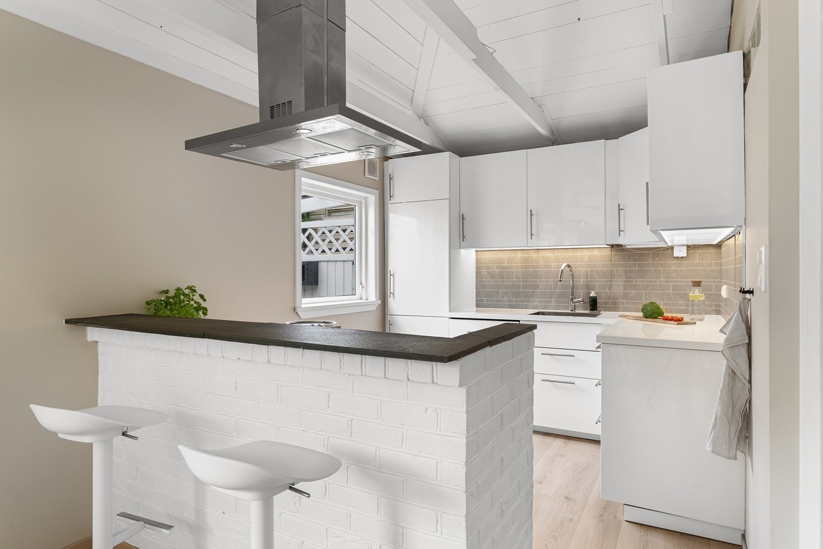 En kjøkkenøy gir en naturlig avdeling mot stuedelen av rommet og her er det en trivelig frokostplass ved den ene enden. Galleribilde