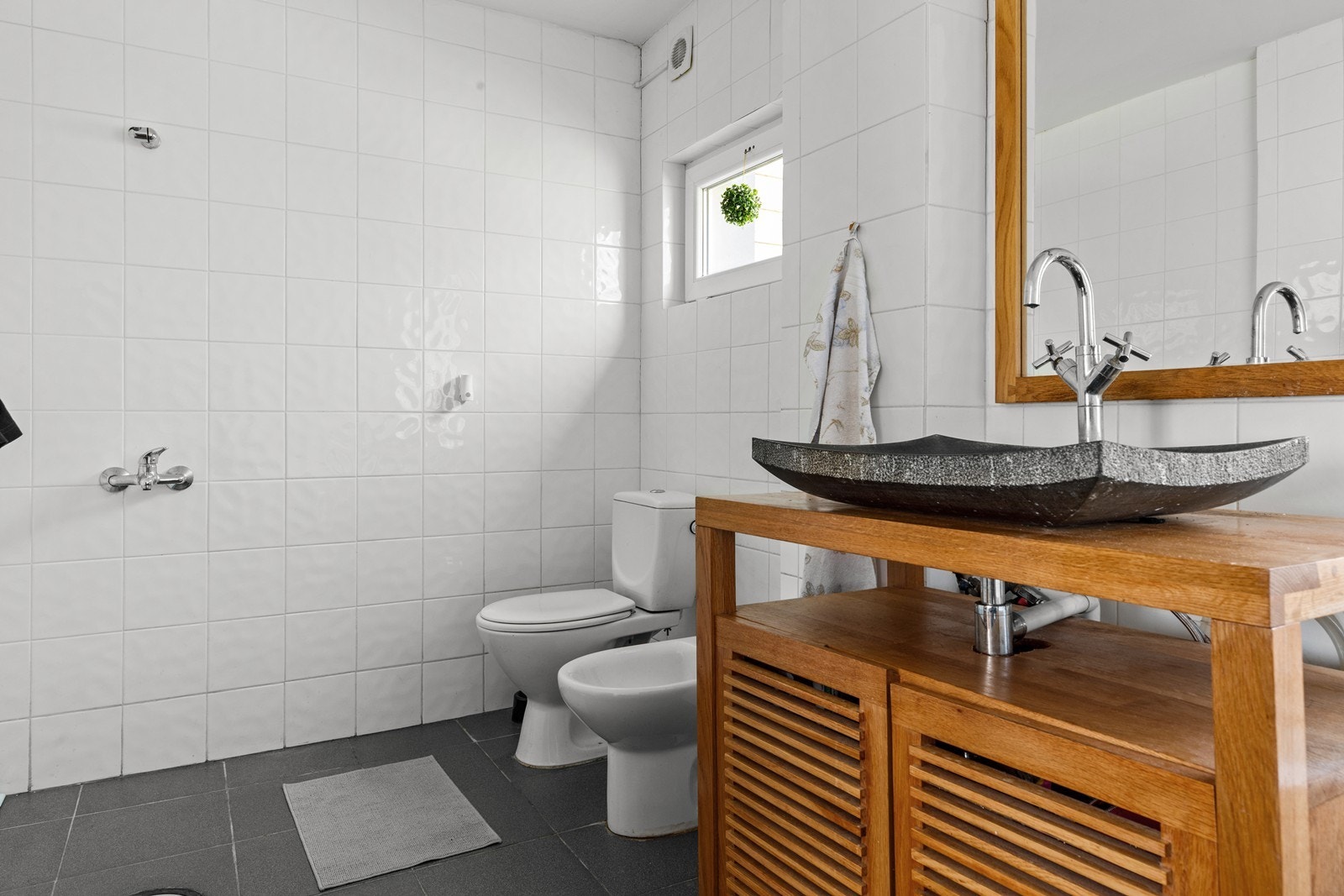 Badet er innredet med servant på skap, stående toallet og badekar. Galleribilde