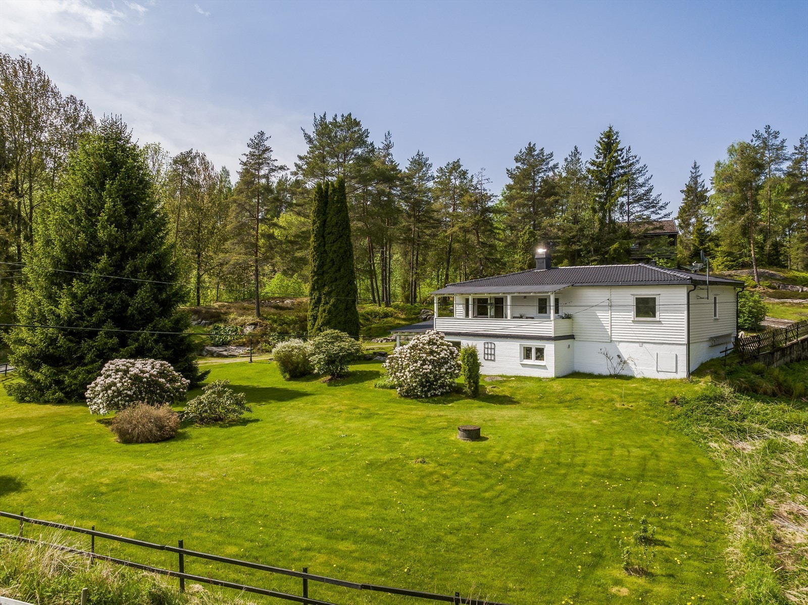 Naturtomt med fjell og skog. Det er gruset innkjørsel og parkering i garasje. Galleribilde