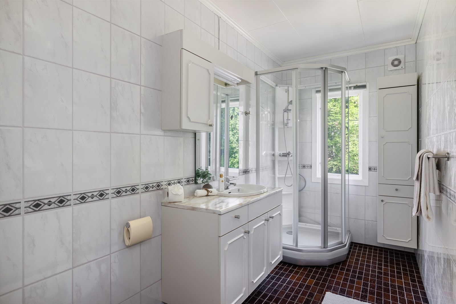 Badet inneholder toalett, dusjkabinett og servantinnredning med underskap, overskap, høyskap og speil med overlys og El-stikk. Galleribilde