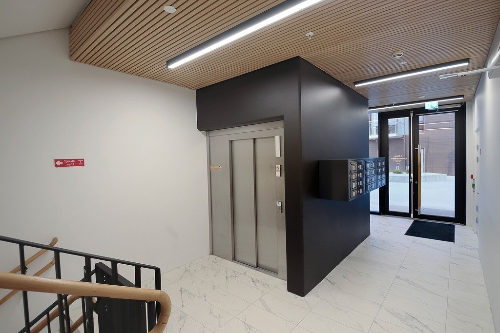 Bygget har heis og trappegang til gateplan med dørtelefon og postkasser Galleribilde