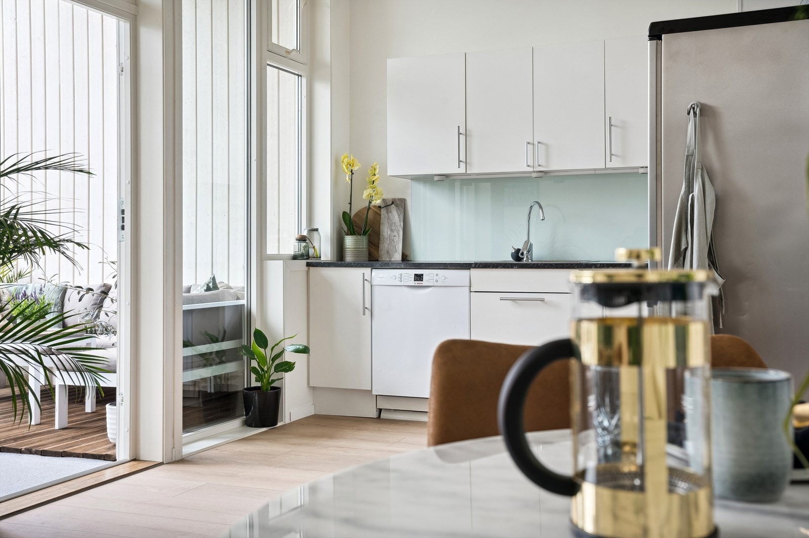 Tidløst kjøkken med hvite fronter, sort benkeplate og nedfelt kum i rustfritt stål. Galleribilde