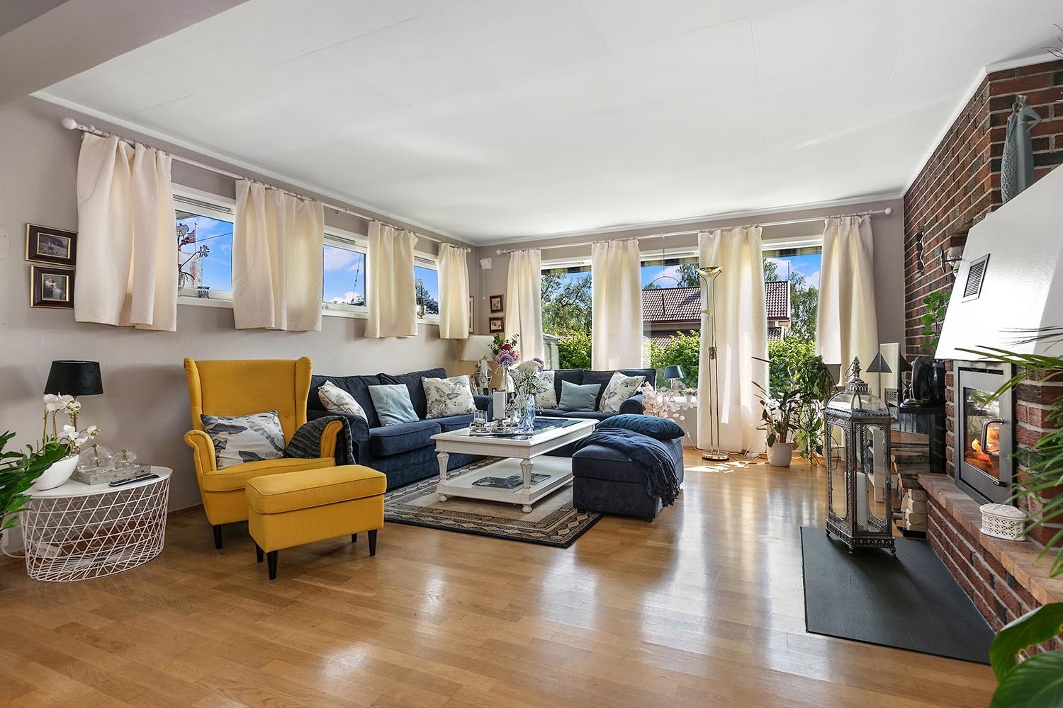 Stor stue med murt peis i åpen løsning med spisestue med utgang til solrik terrasse og hagen Galleribilde