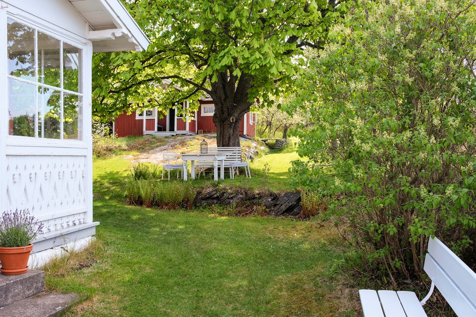 De mange forskjellige uteplassene er skjermet i fohold til varierende sol- og vindretning. Her under det store tuntreet. Galleribilde