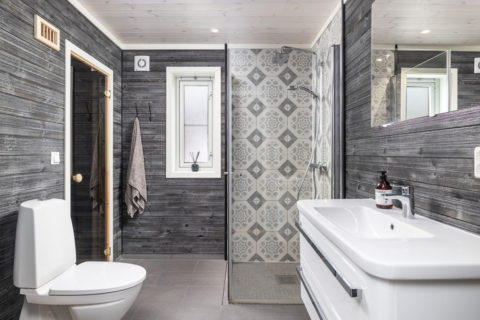 Badet har fliser på gulv m/ elektriske varmekabler, panel på vegger og i tak og fliser på vegg i dusjsone. Galleribilde