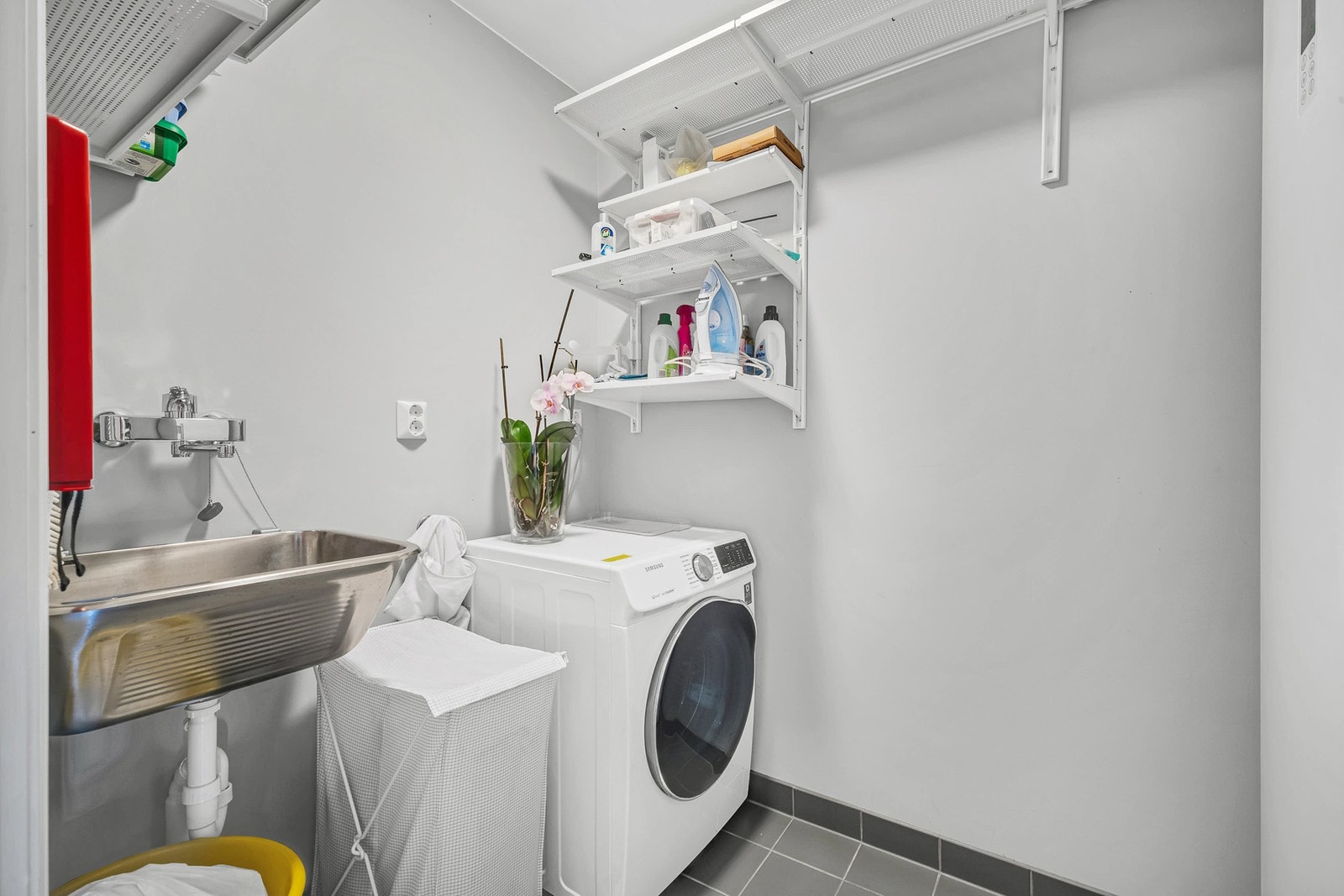 Praktisk avdelt vaskerom med utslagsvask, opplegg for vaskemaskin og hyllesystem. Galleribilde