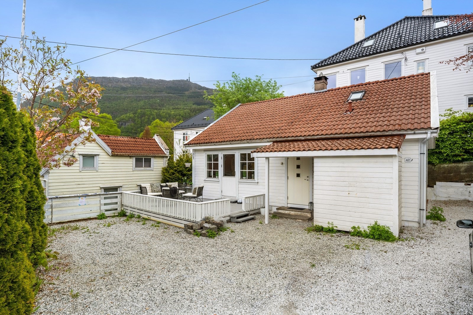 Pent opparbeidet tomt med terrasse, forstøtningsmurer og gruset parkering Galleribilde