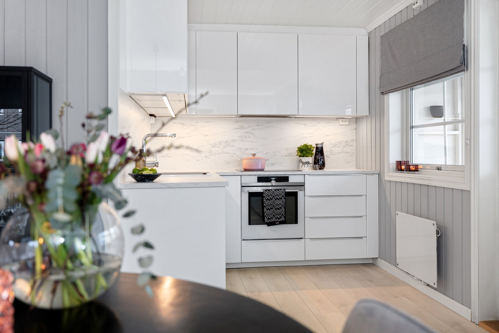 Lyst og fint kjøkken fra 2017 med innredning bestående av lyse, slette fronter og laminert benkeplate. Det er plateslåtte flater mellom over og underskap, enkel porselenservant med ettgreps blandebatteri, integrerte kjøleskuffer, koketopp og komfyr. Galleribilde