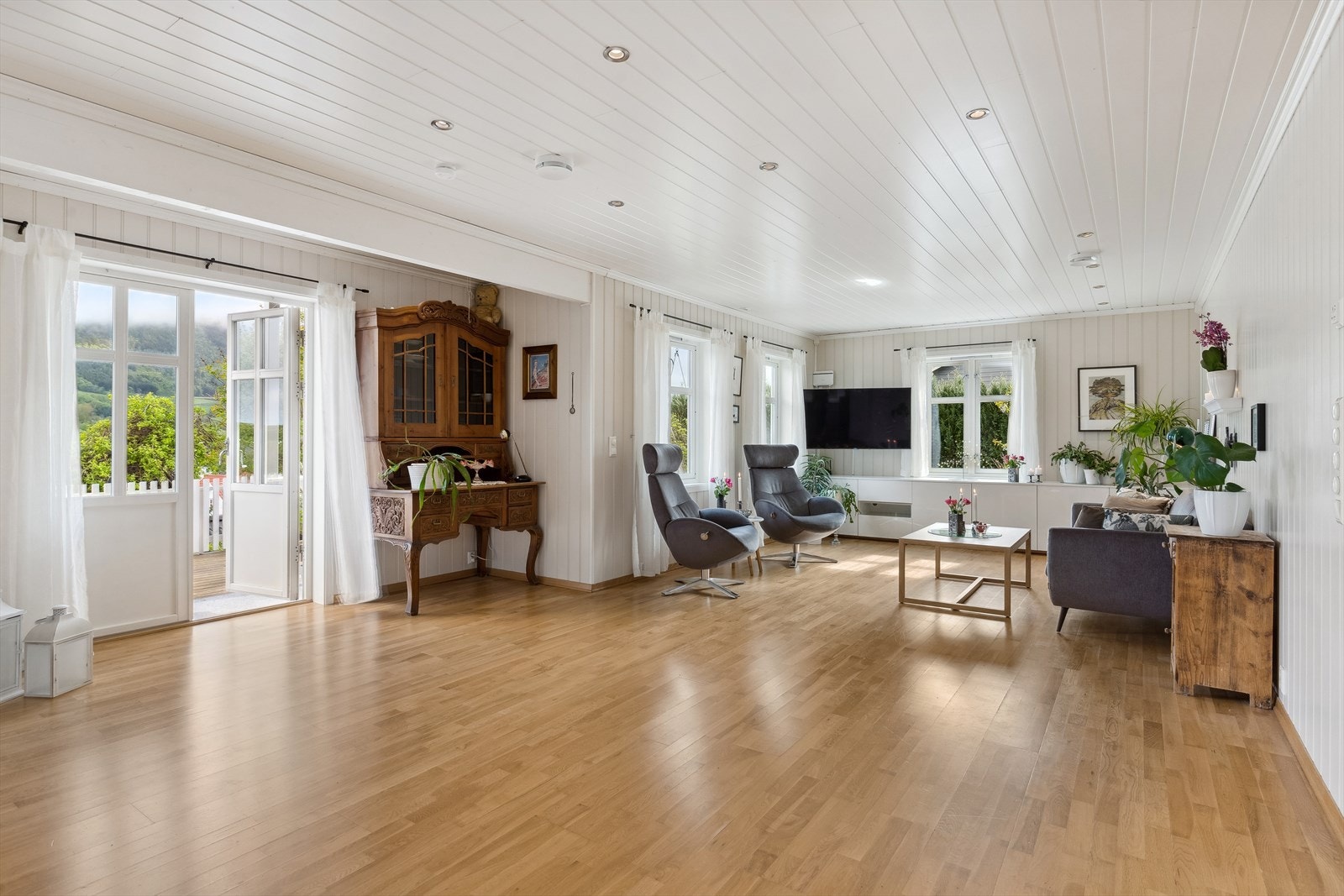 Stue med store vindusflater som gir mye naturlig lysinnslipp og bidrar til en behagelig romfølelse. Galleribilde