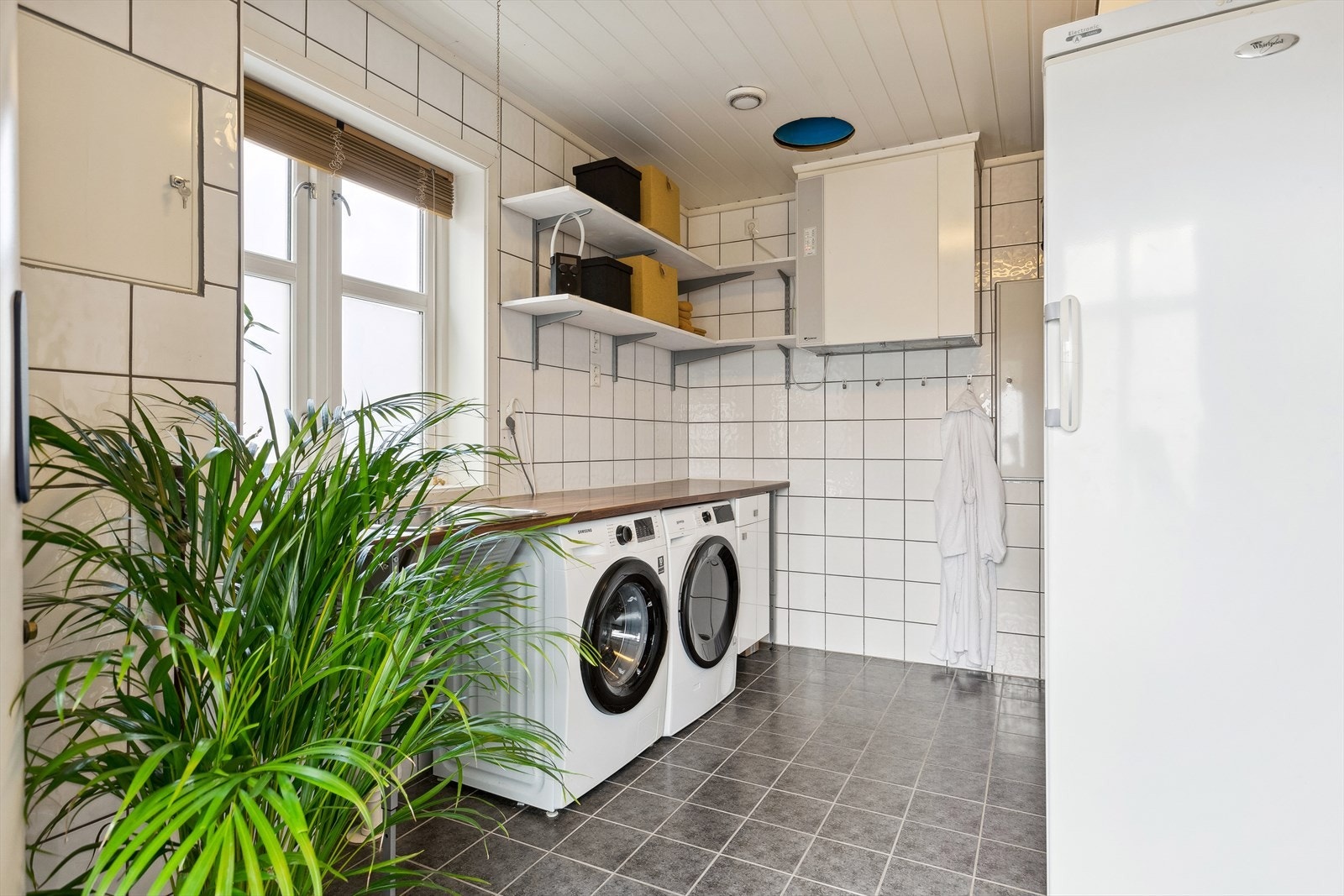 Bad/vaskerom med flis på vegger og panel innvendig i tak. Hull i tak for skittentøy sjakt fra ovenforliggende bad Galleribilde