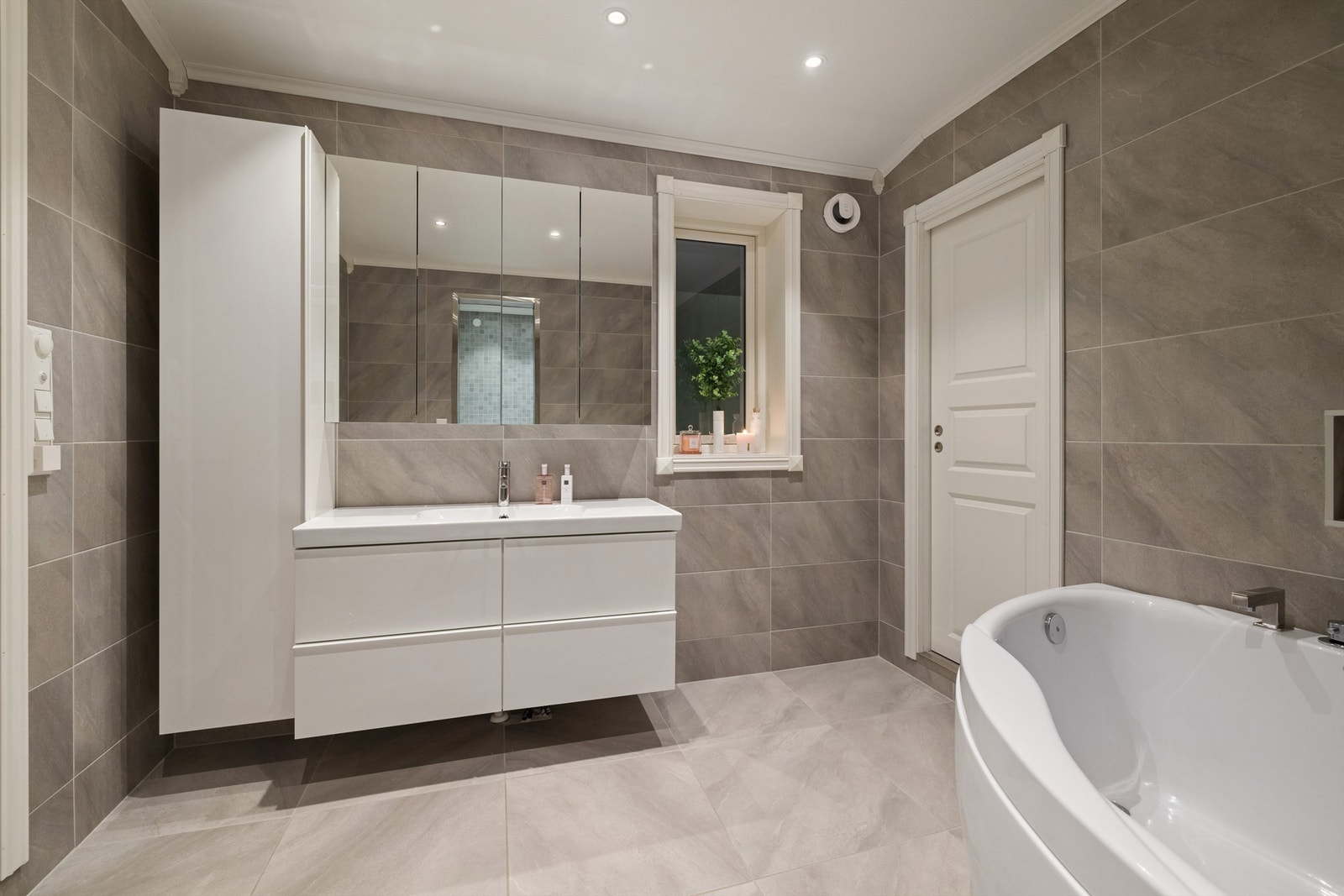 Badet er utstyrt med toalett, badekar og innredning med servant Galleribilde