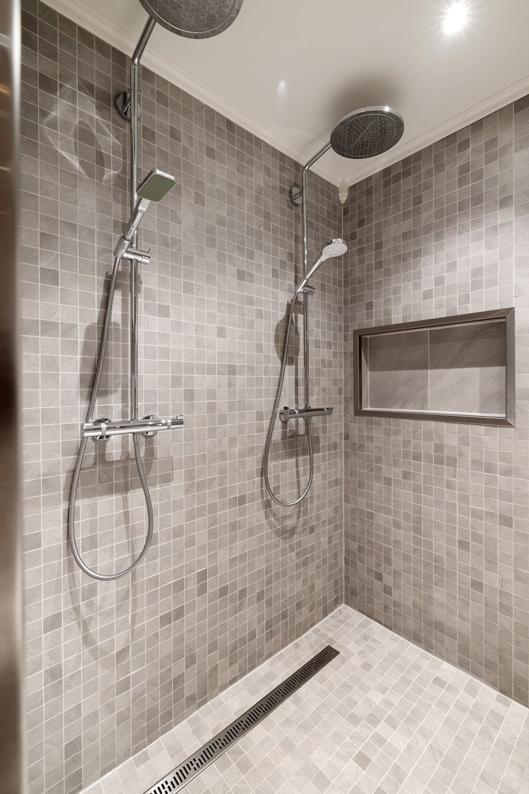 Dusjrommet har 2 veggmonterte dusjer, og egen nisje i veggen for såper og sjampo Galleribilde