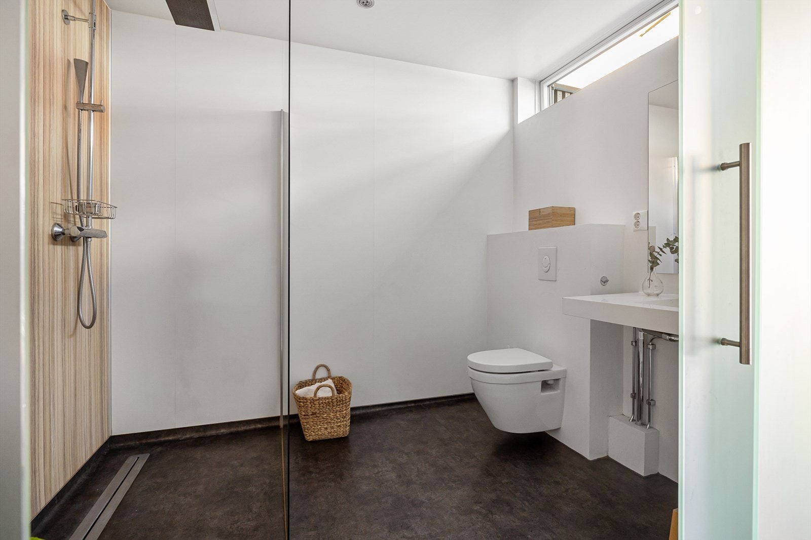 Badet er innredet med servant, vegghengt toalett og regnfallsdusj med spesialbestilt dusjvegg. Galleribilde