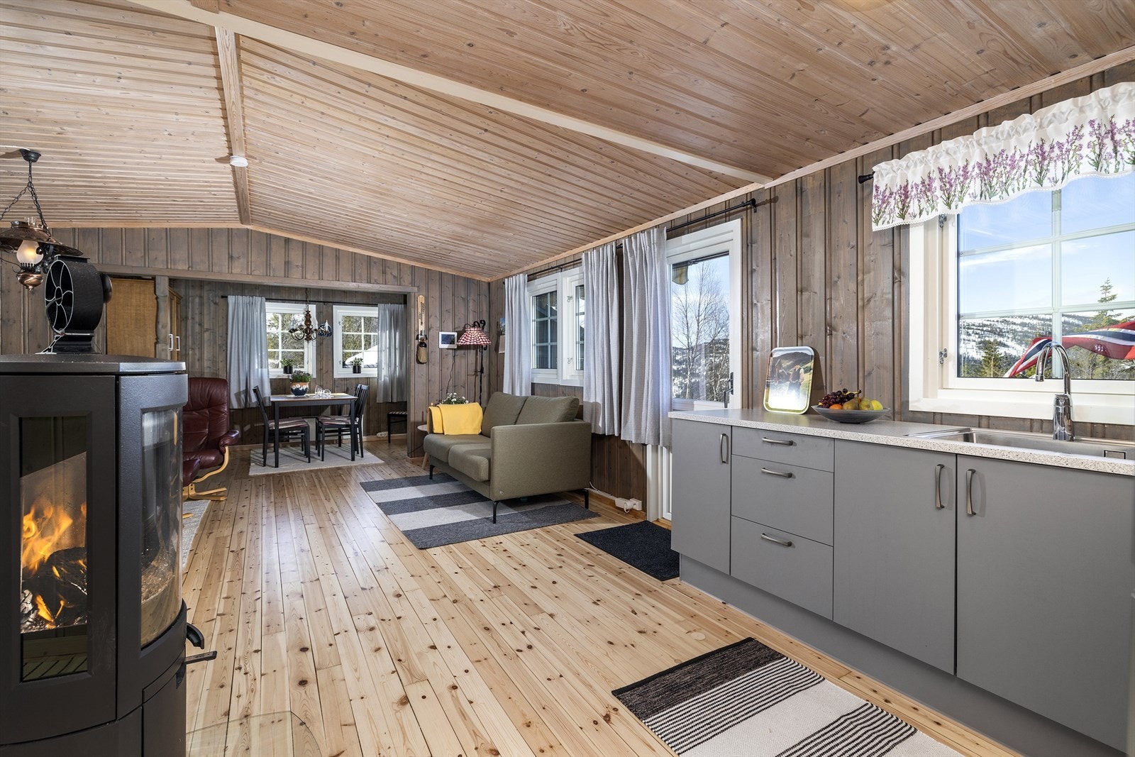 Mellom kjøkkenet og stuen er det montert en stemningsfull peisovn. Galleribilde