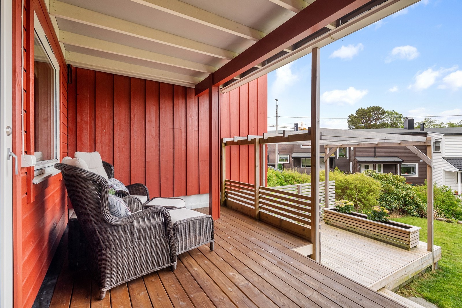 Overbygd veranda med trapp ned til platting med pergola og en passelig stor hage Galleribilde