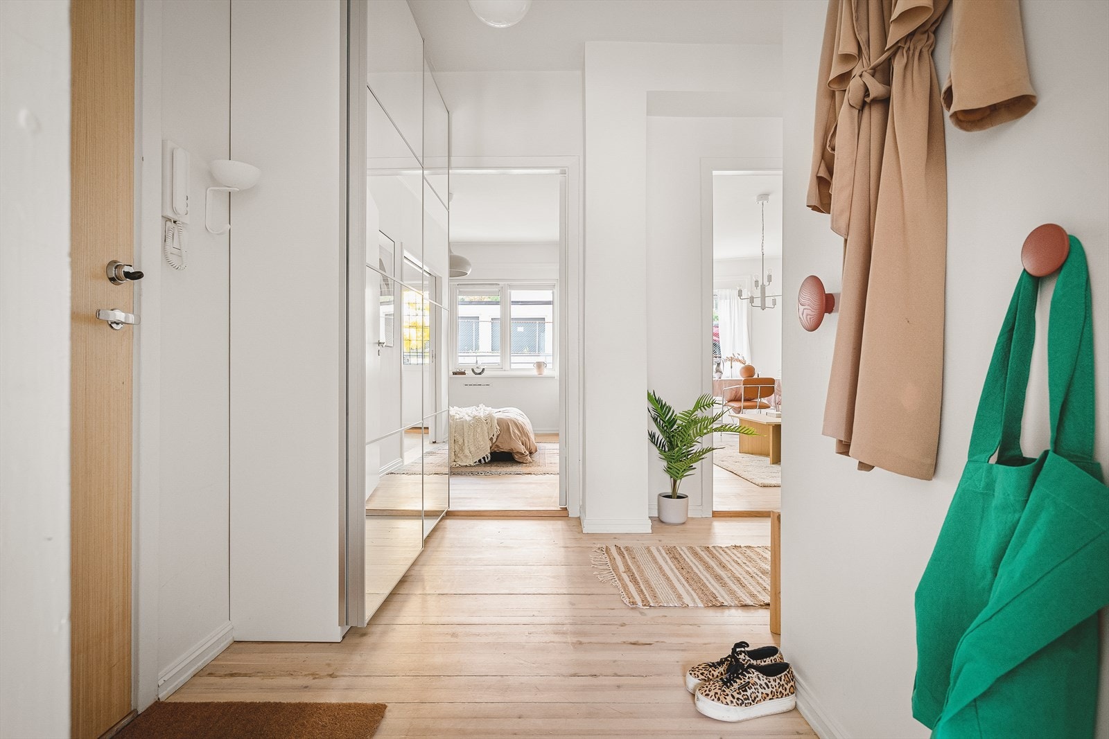 Romslig og tiltalende entré med lyse vegger og tregulv. Her har man god plass til oppbevaring av klær i en praktisk skyvedørsgarderobe. Galleribilde