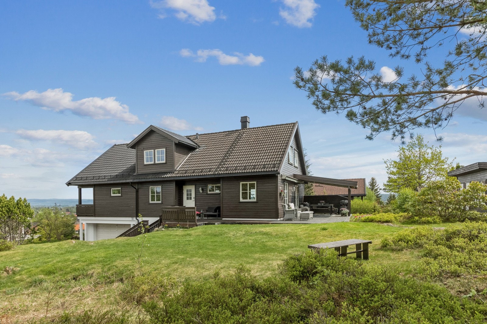 Utenfor er det en nydelig uteplass med stor terrasse og romslig hage som grenser mot friområde. Galleribilde