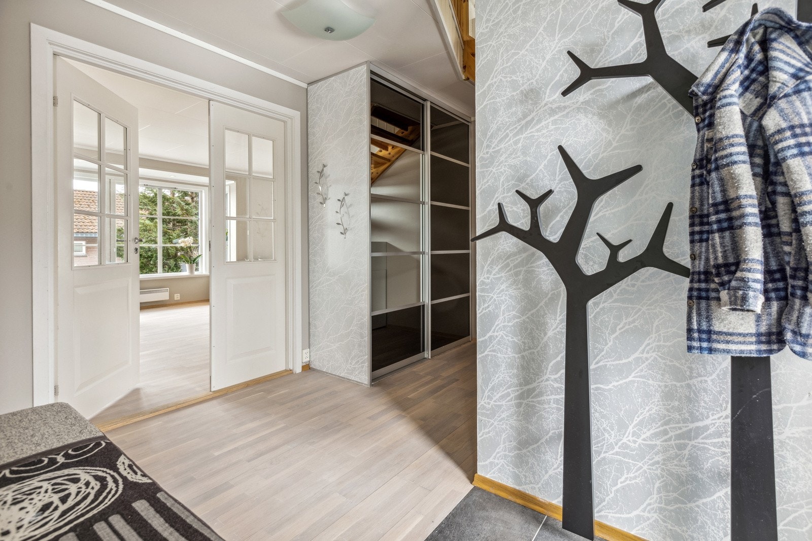 Innbydende entrè/ hall med nyfliset gulv. Her er det god plass til yttertøy og sko. Det er rikelig med oppbevaringsplass i skyvedørsgarderobe i gang. Videre er det en dobbelfløyet vitrinedør mot stuen. Galleribilde