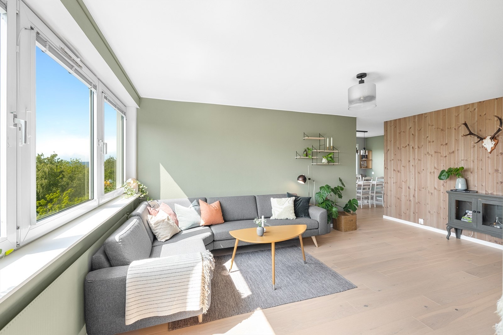 Stue med parkett på gulv, 1 vegg med beiset panel, malte slette vegger og mal tak. Stuen er enkel og møblere og med store vindusflater føles den som lys og luftig som skaper en hyggelig atmosfære. Galleribilde