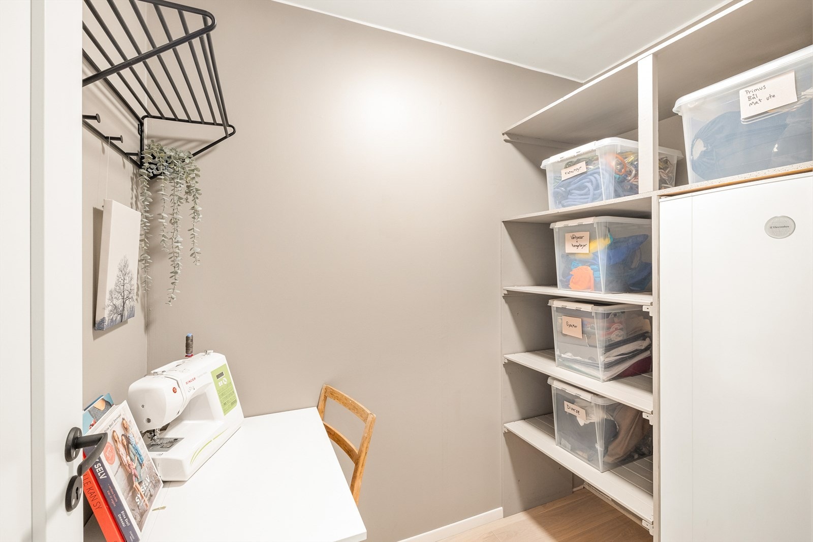 Garderobe/bod med parkett på gulv, malte slette vegger og malt tak. Romslig og praktisk med plassbygde hylleløsninger og fryseskap som følger ved salg. Galleribilde
