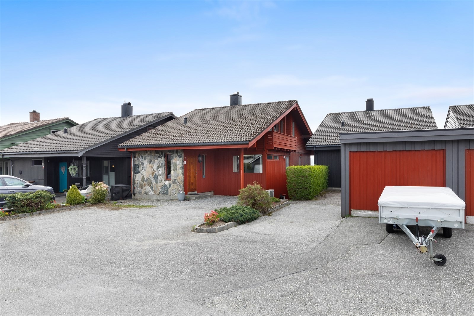 Eiendommen inkluderer også parkering i gårdsrom samt egen garasje (den med tilhenger foran). Galleribilde