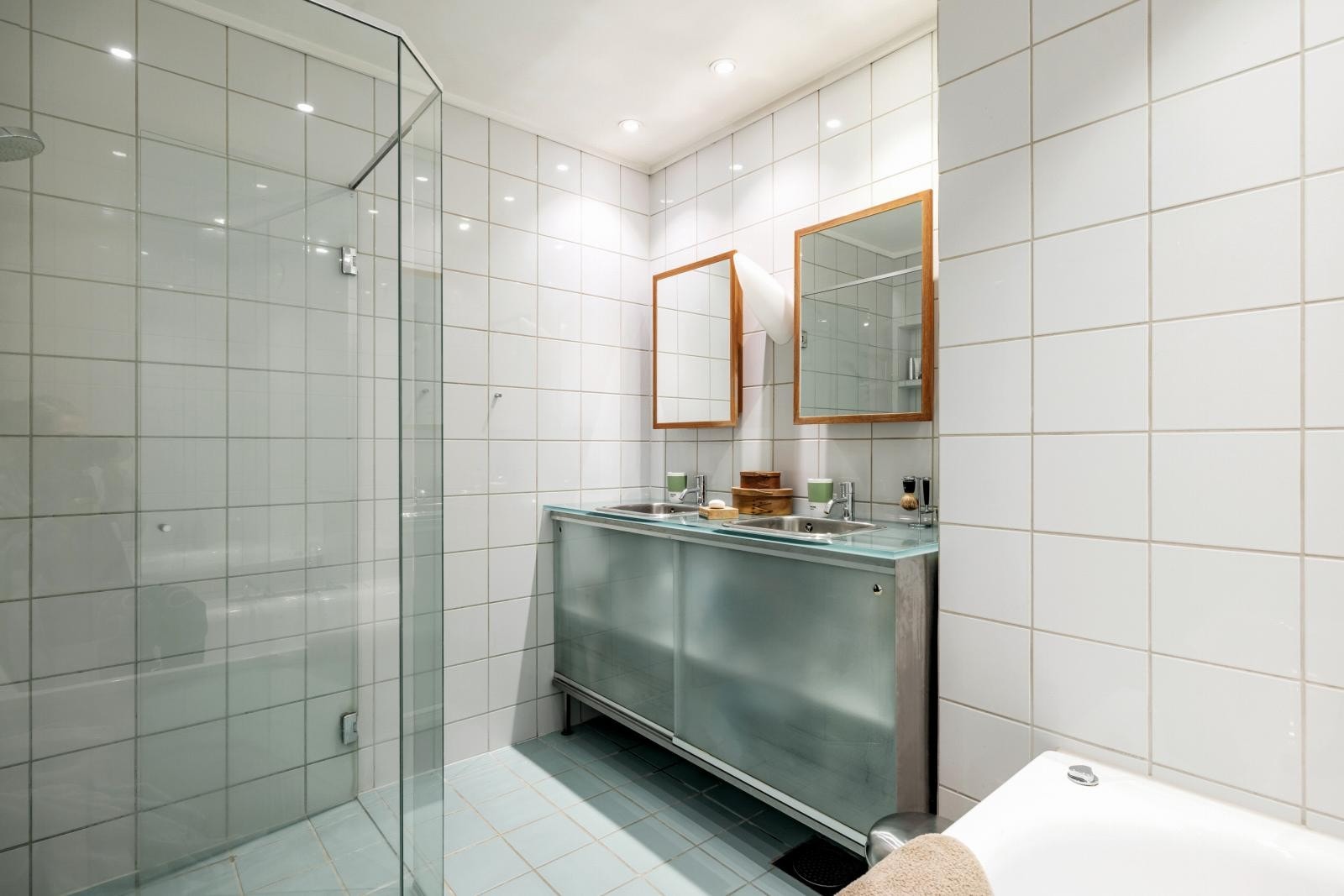 Hovedbadet i 2. etasje med varmekabler. Her er det dobbel vask med underskap i stål og frostet, herdet glass, to speilskap i teak, dusjhjørne med faste glassvegger og dør, samt et stort innfliset badekar. Galleribilde