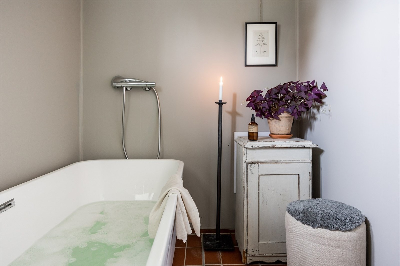 Badet har flislagt gulv med varmekabler, malte våtromsplater, badekar, vegghengt toalett og nedfelt servant. Galleribilde