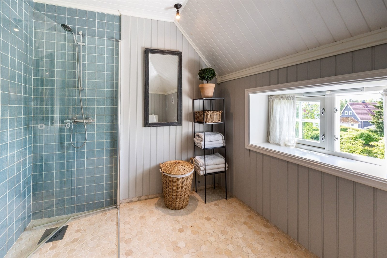 Badet har flislagt gulv med varmekabler, flislagt dusjsone, svingbare dusjdører, toalett, servantskap, panel i tak og på øvrige vegger. Galleribilde
