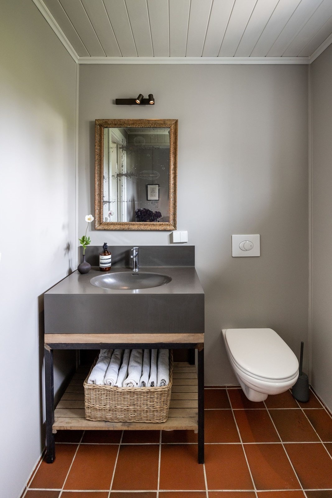 Badet har flislagt gulv med varmekabler, malte våtromsplater, badekar, vegghengt toalett og nedfelt servant. Galleribilde