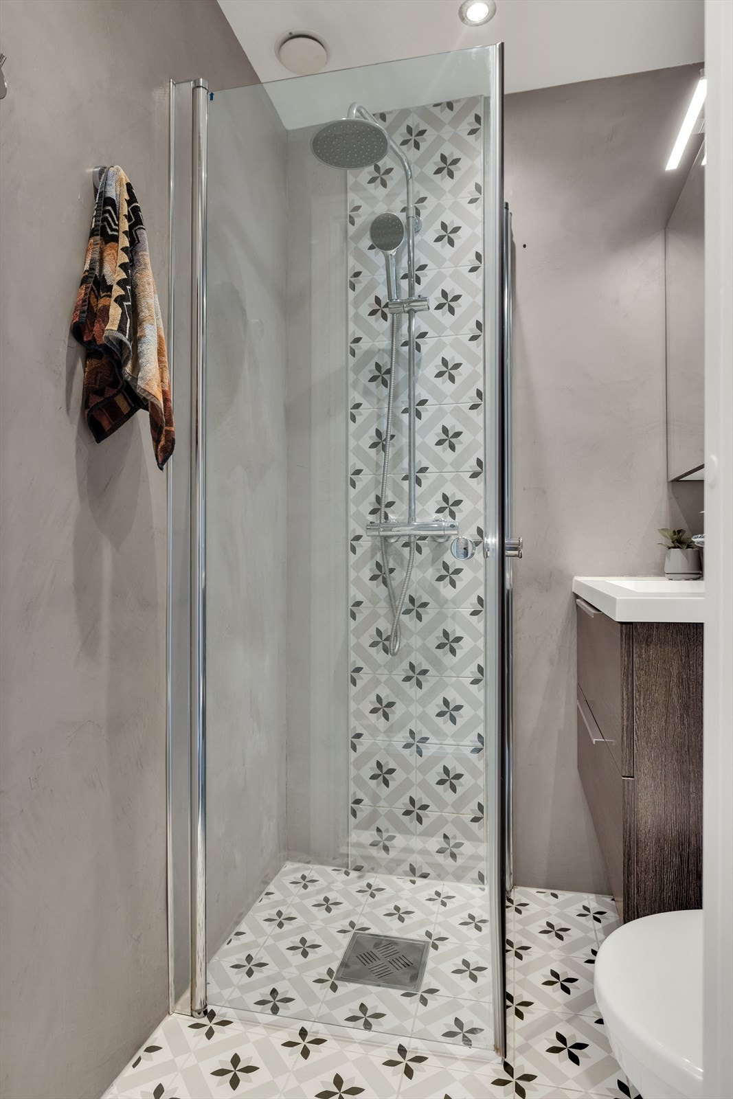 Videre har badet dusj på gulv, med innfellbare glassdører Galleribilde