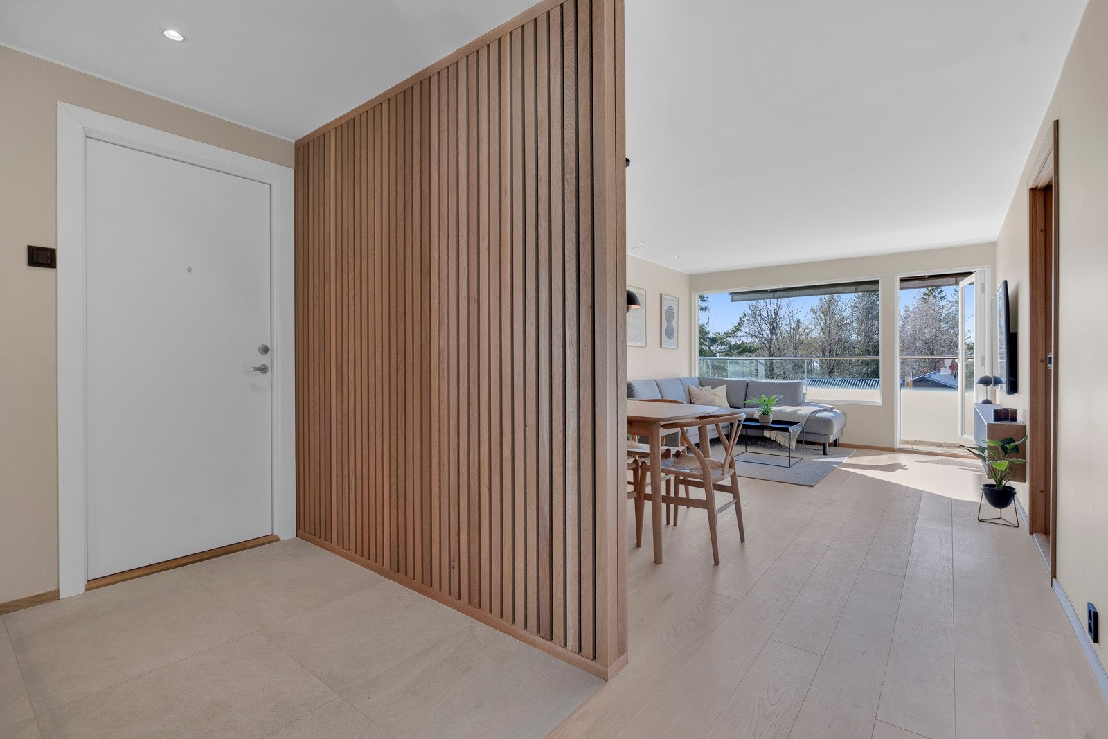 Stue og entré skilles av en moderne spilevegg med heltre eikespiler. Galleribilde