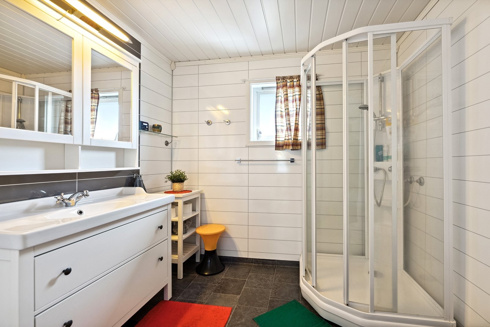 Badet har innredning med heldekkende servant og ett-greps blandebatteri, speilskap med overliggende belysning, dusjkabinett og
gulvmontert toalett. Galleribilde
