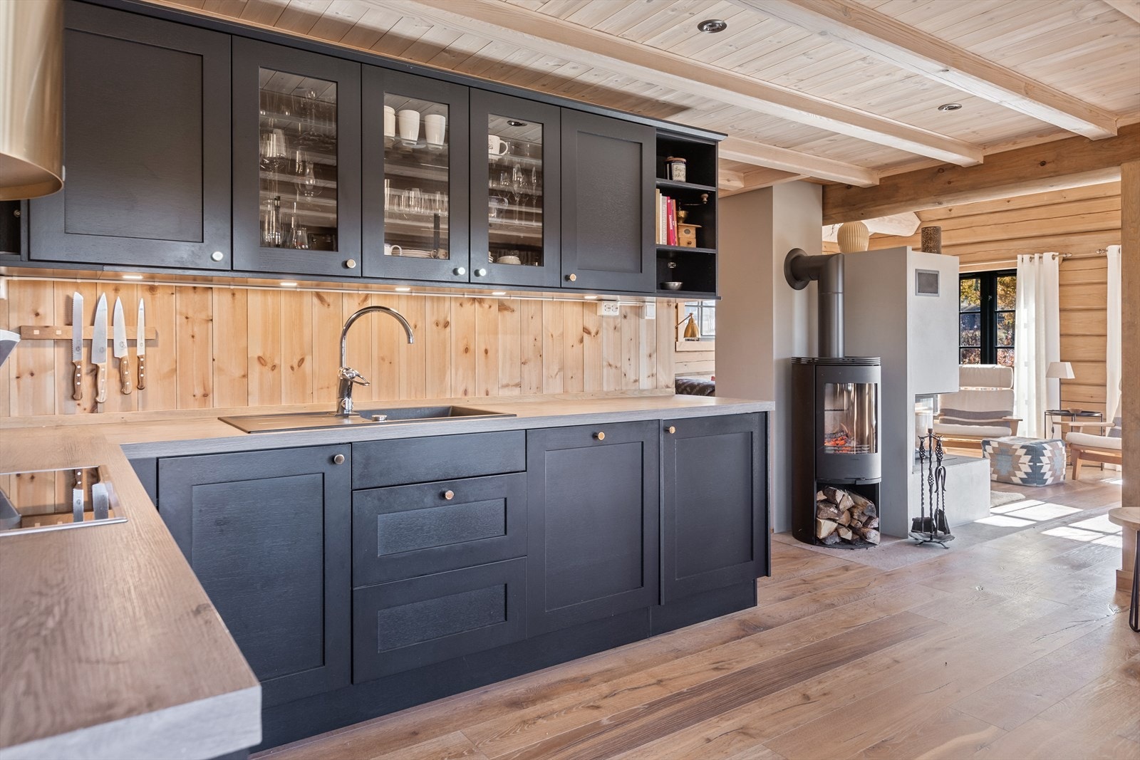 Lekkert kjøkken i mørk eik med integrerte hvitevarer. Hyggelig peisovn i tilknytning til kjøkkenet Galleribilde