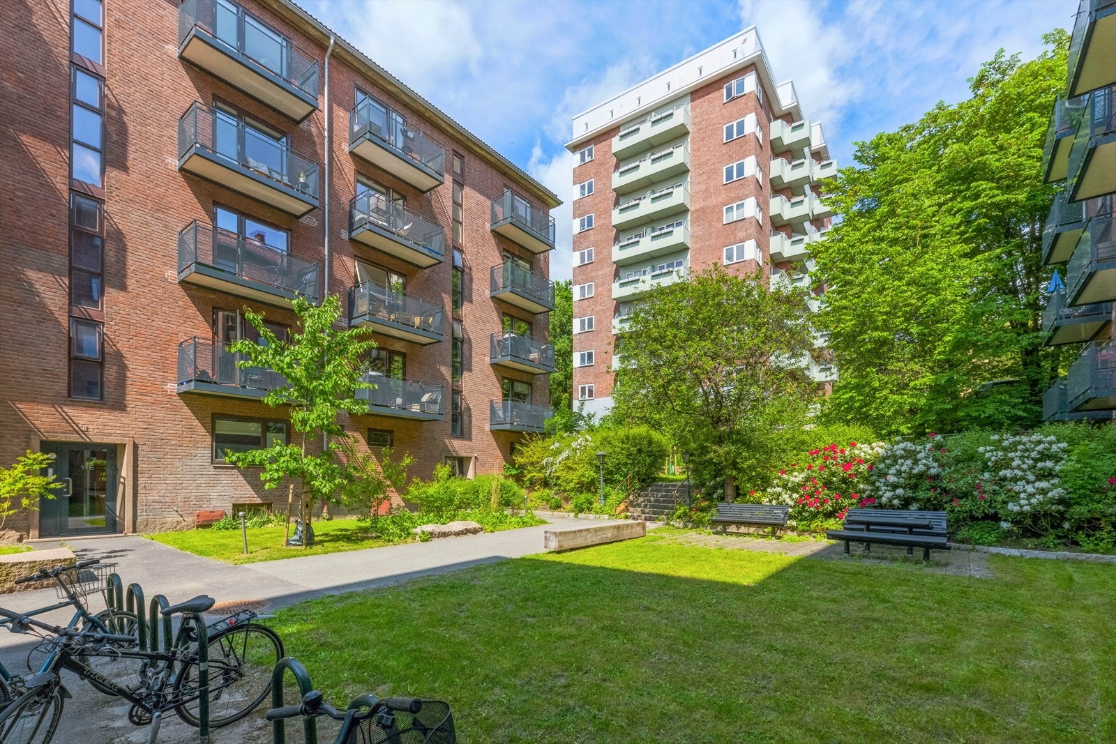 Hyggelig og grønt fellesområde med flere sittegrupper og sykkelparkering Galleribilde