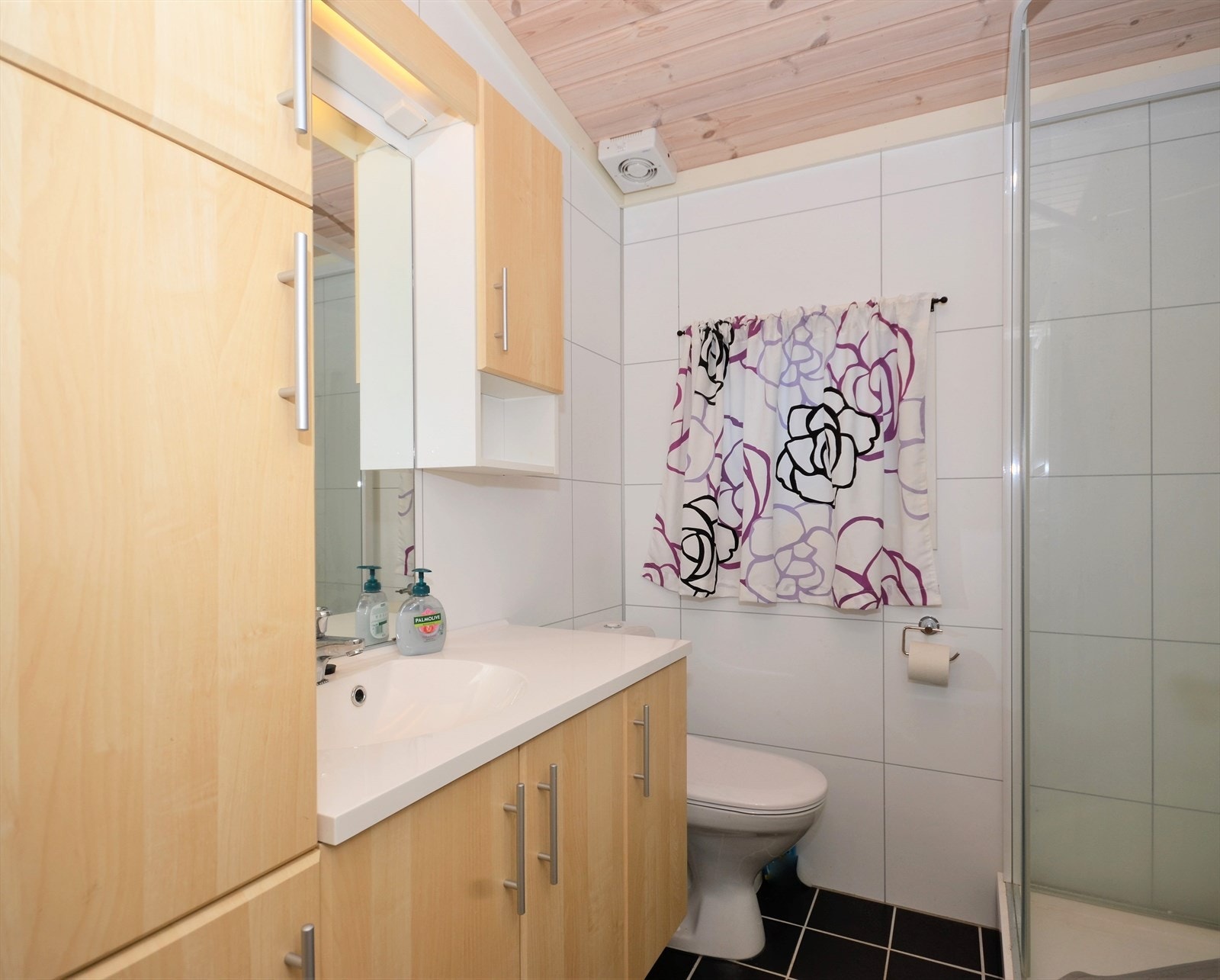 Badet er innredet med dusjkabinett, servant på innredning og toalett. Galleribilde