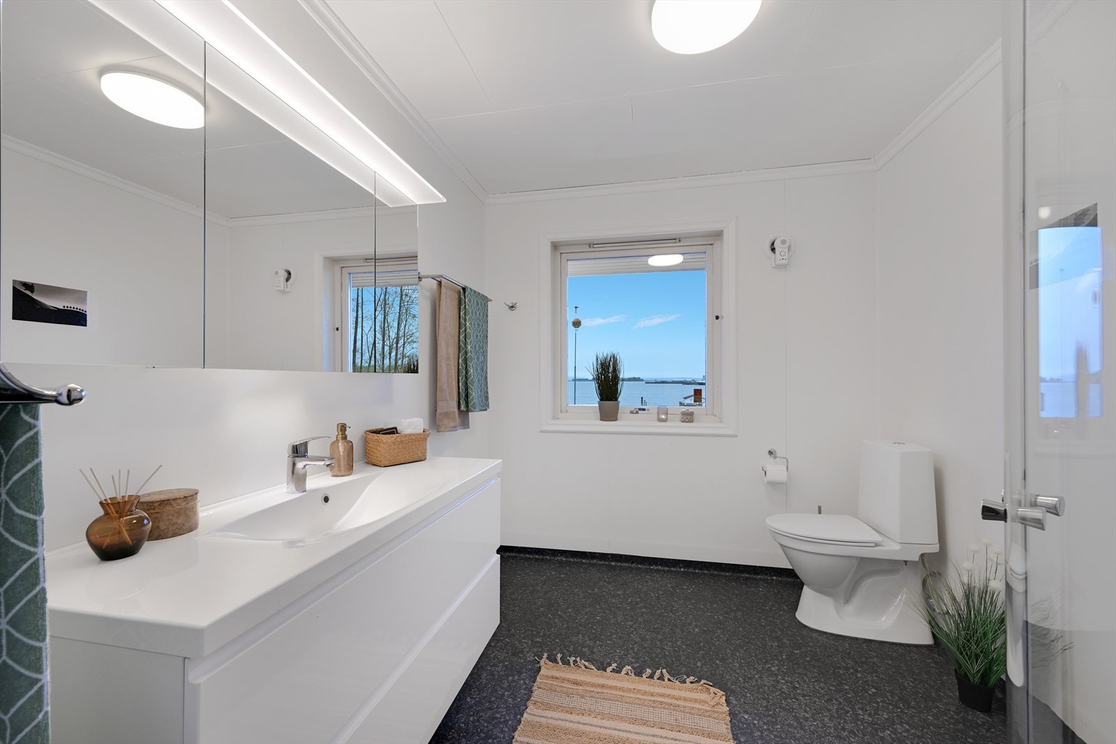 Nytt (2020) bad/wc med belegg og nye varmekabler på gulv, dusjhjørne, wc, servant i innredning med skuffer, speilskap. Galleribilde