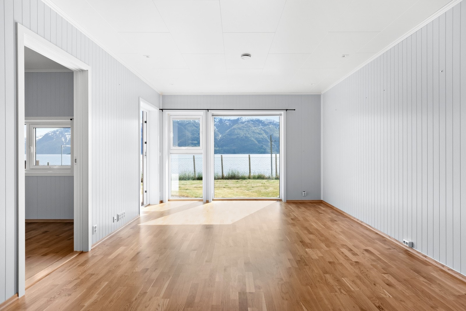 Rommet er lyst og fint med store vindauger med flott utsikt ut over fjorden. Det er peisovn i stova. Galleribilde