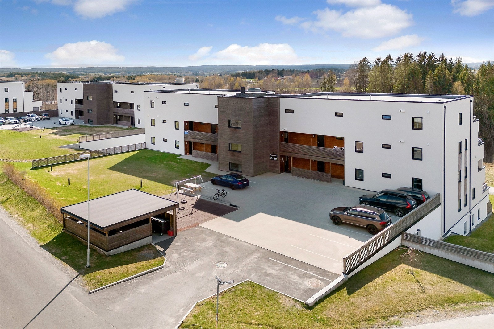 Hyggelig fellesområder med p-plasser, plen, sittebenker, lekeapparater og div. beplantning Galleribilde