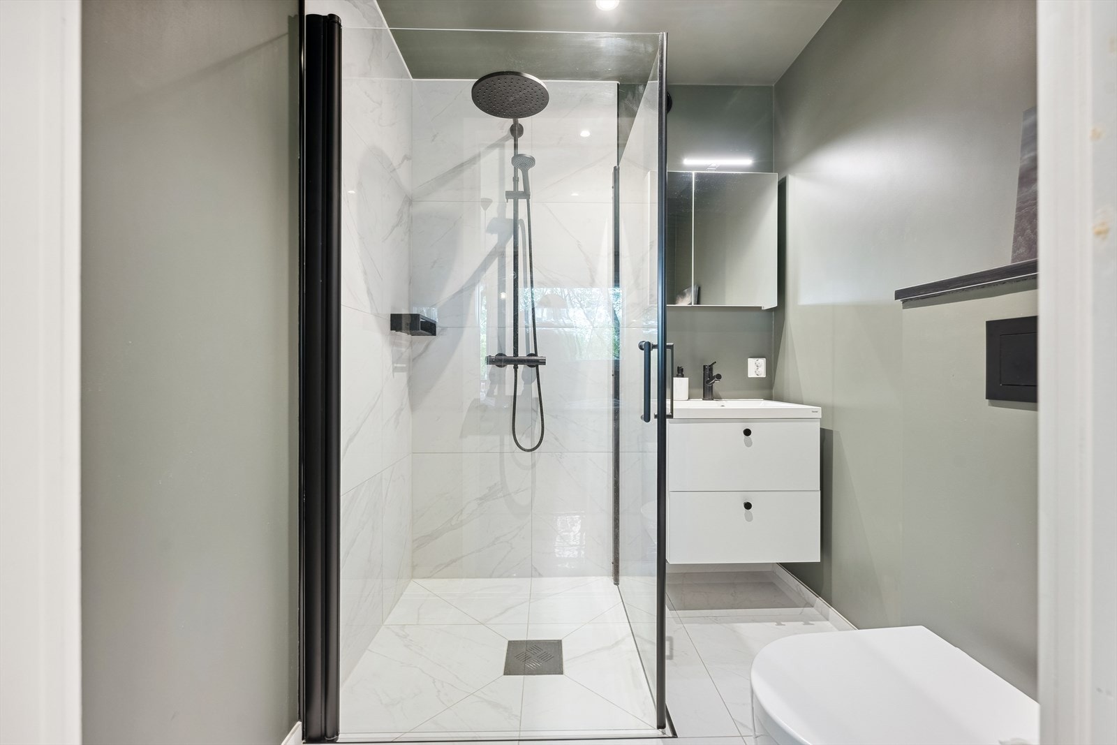 Masterbadet er renovert i 2020 og har fliser på gulv med varmekabler, innredet med toalett, dusjhjørne med fliser og glassvegger, samt innredning med servant. Galleribilde
