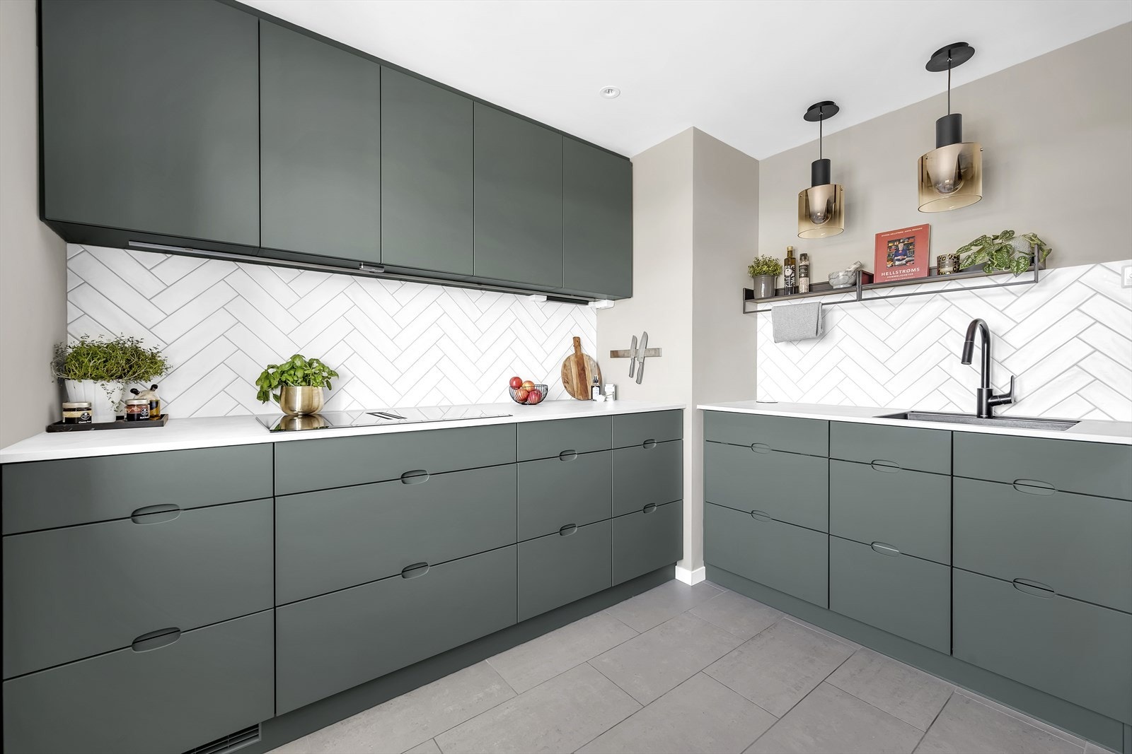 Meget delikat KVIK kjøkken med Ombra Green fronter, hvit fiskebenflis på vegg, matt sort Hansgrohe Focus kjøkkenarmatur og Smart Induksjonsplatetopp med integrert ventilasjon. Galleribilde