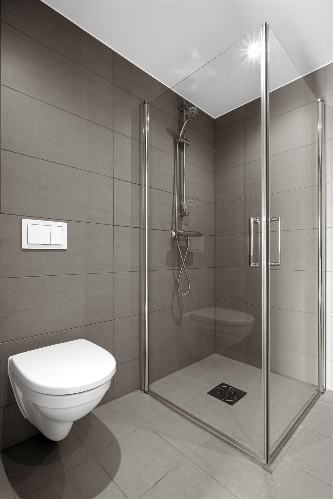 Badet er blant annet innredet med vegghengt toalett, dusjhjørne og flislagte vegger i en matt gråfarge (Minos Ash). Det er opplegg for, og avsatt plass til vaskemaskin. Galleribilde