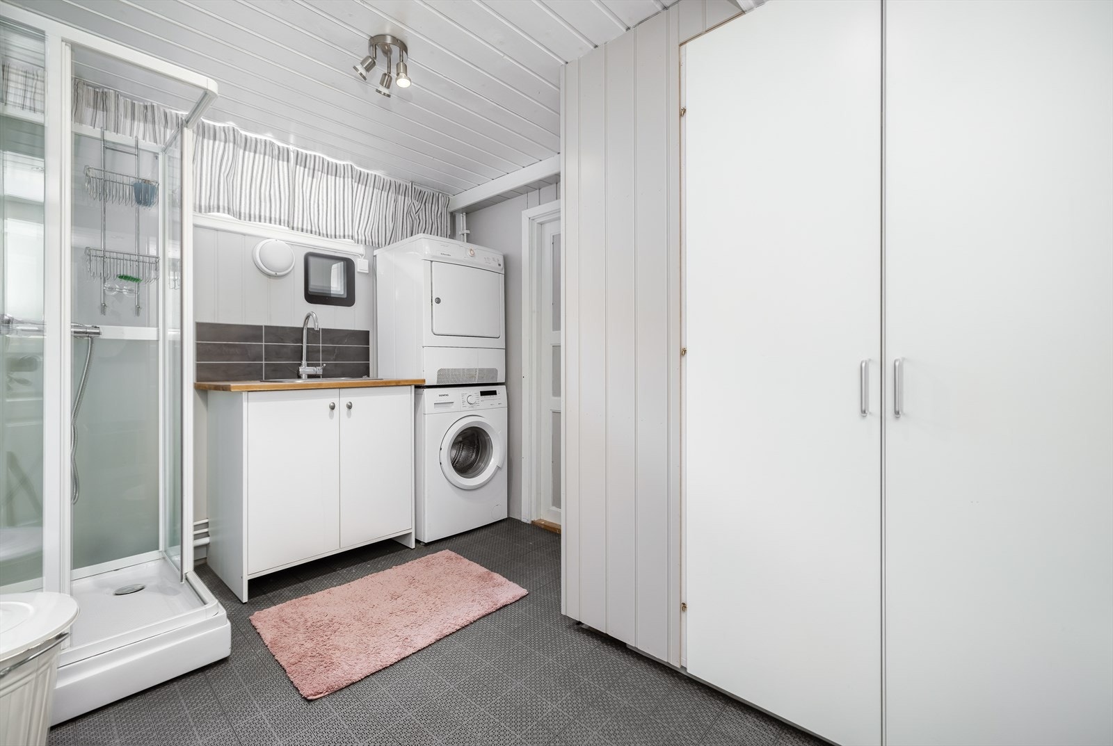 Rommet er utstyrt med et nytt dusjkabinett, servant med skap under, opplegg for vaskemaskin og praktisk plassering i skap av to varmtvannstanker, en til hver etasje. Galleribilde