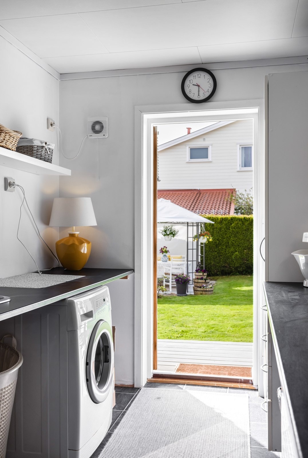 Det er et praktisk vaskerom i 1. etasje med utgang til platting og hage. Her er det innredning på begge sider med laminat benkeplate og nedfelt utslagsvask i rustfritt stål på den ene siden. Opplegg og plass for vaskemaskin Galleribilde
