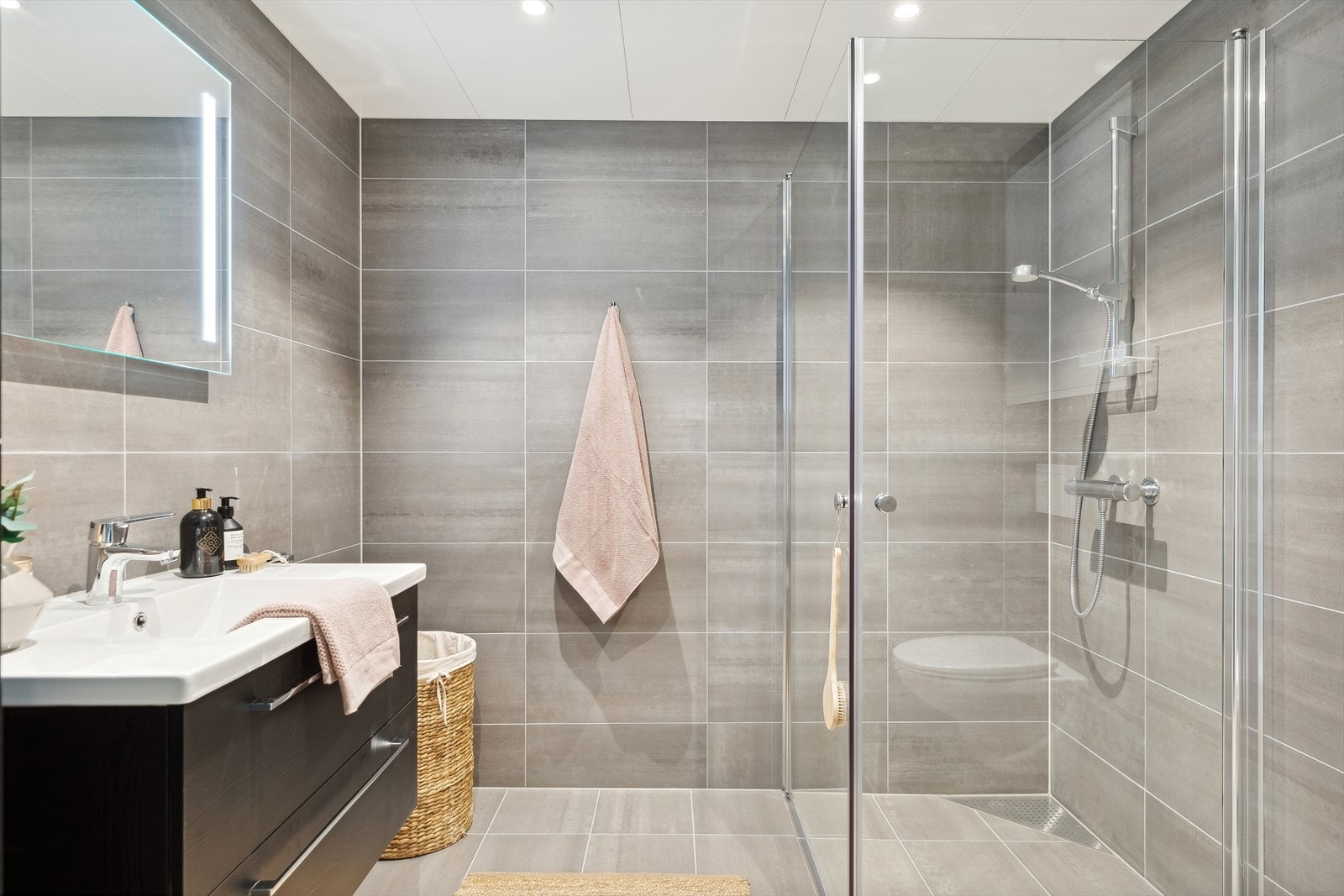 Badet har delikat utførelse med flislagte overflater og hvitmalt himling med downlights. Galleribilde