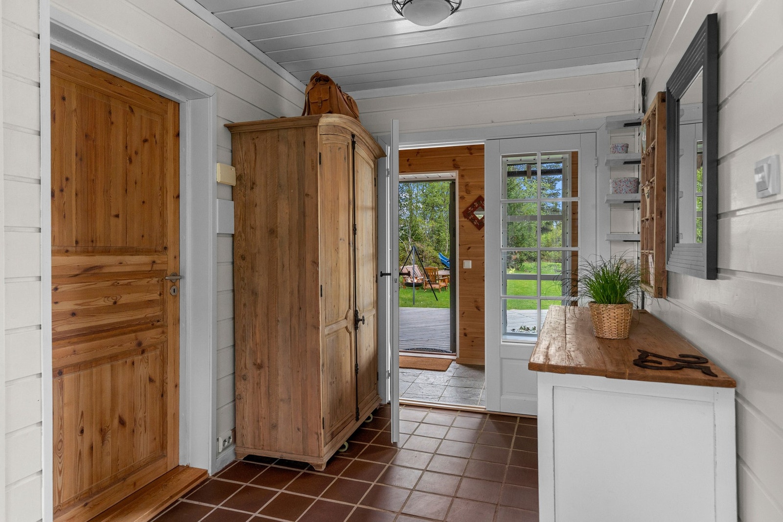 Romslig og flislagt gang/entré med varmekabler og inngang til baderom. Galleribilde
