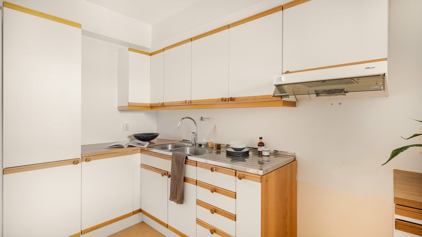 Kjøkkeninnredning med slette fronter, laminat benkeplate, over benkeplaten er det benyttet malte flater, stål oppvaskkum, ventilator. Galleribilde