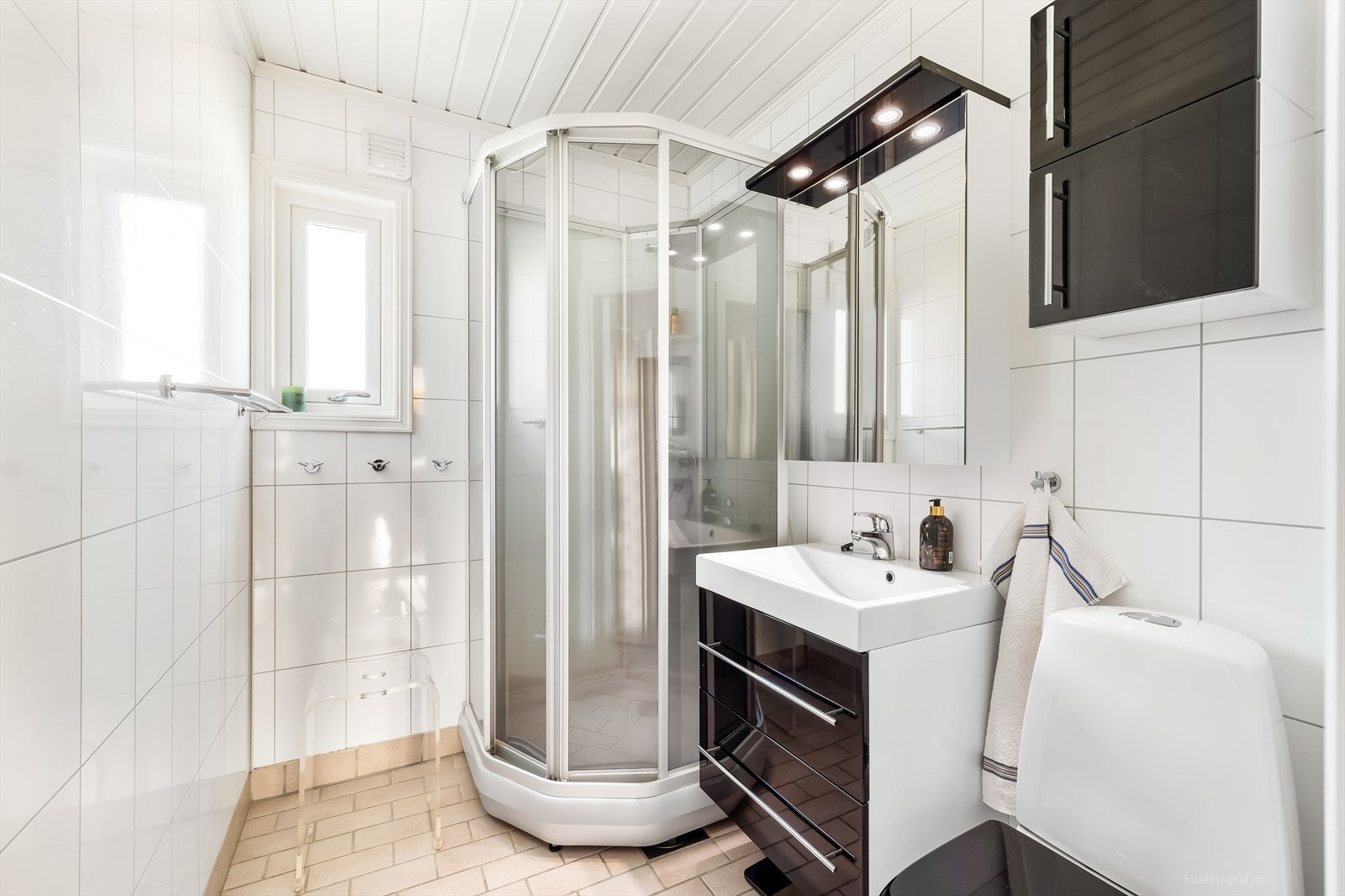 Flislagt bad som er innredet med dusjkabinett, toalett og servant på baderomsinnrending. Galleribilde