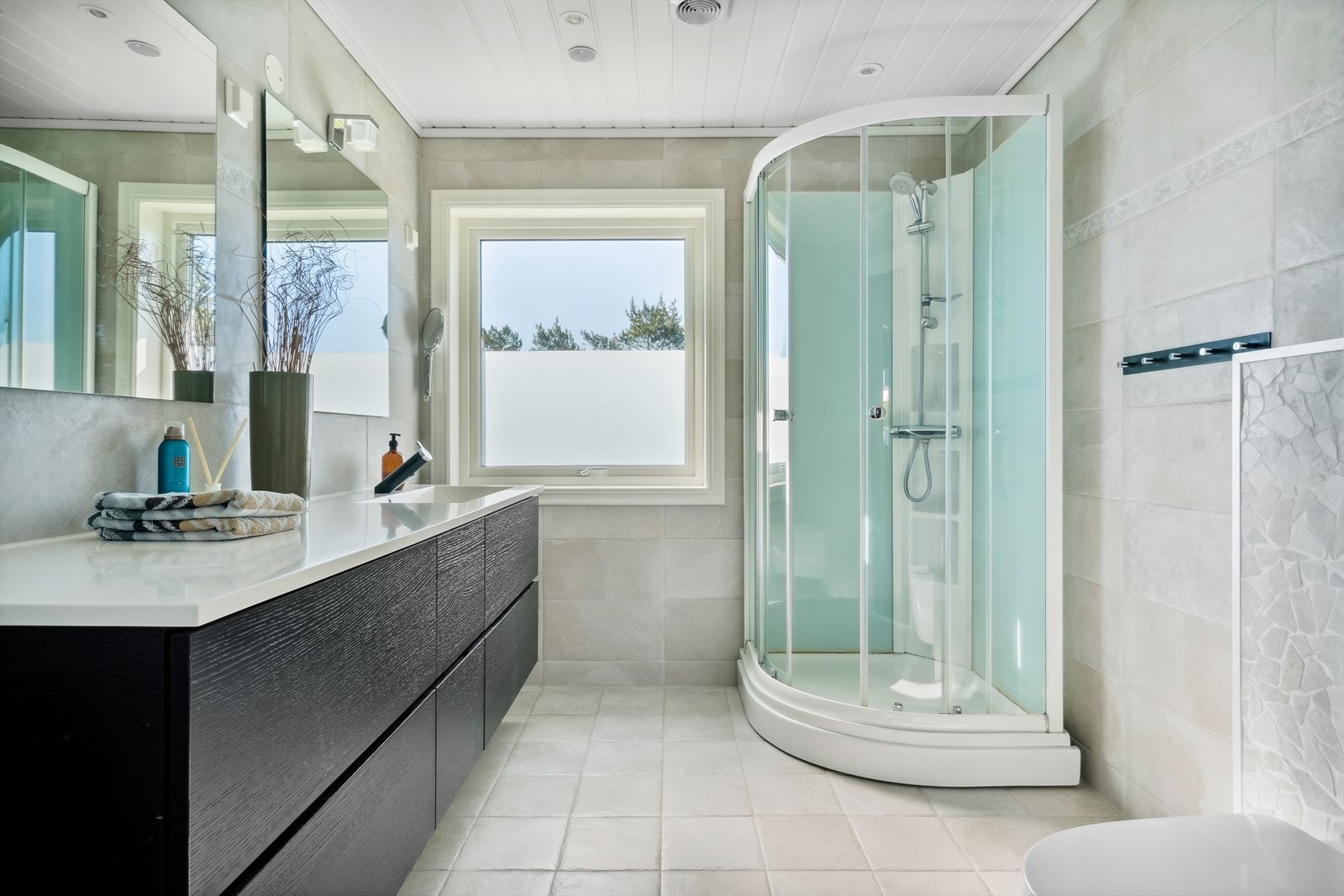 Badet i 1. etasje er innredet med servant med oppbevaringsseksjon, speil, dusjkabinett, vegghengt toalett og dusjkabinett. Galleribilde