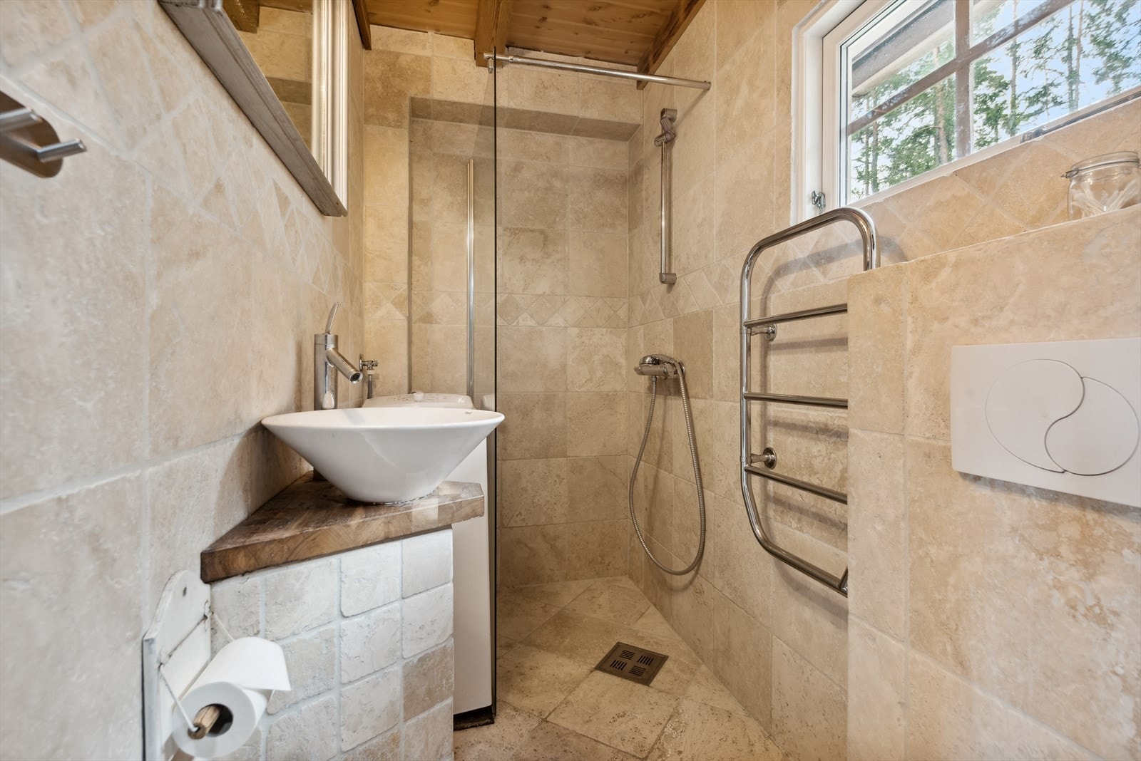 Nydelig helfliset bad med vegghengt toalett, dusjhjørne med glassvegg, opplegg for vaskemaskin og baderomsinnredning med servant Galleribilde